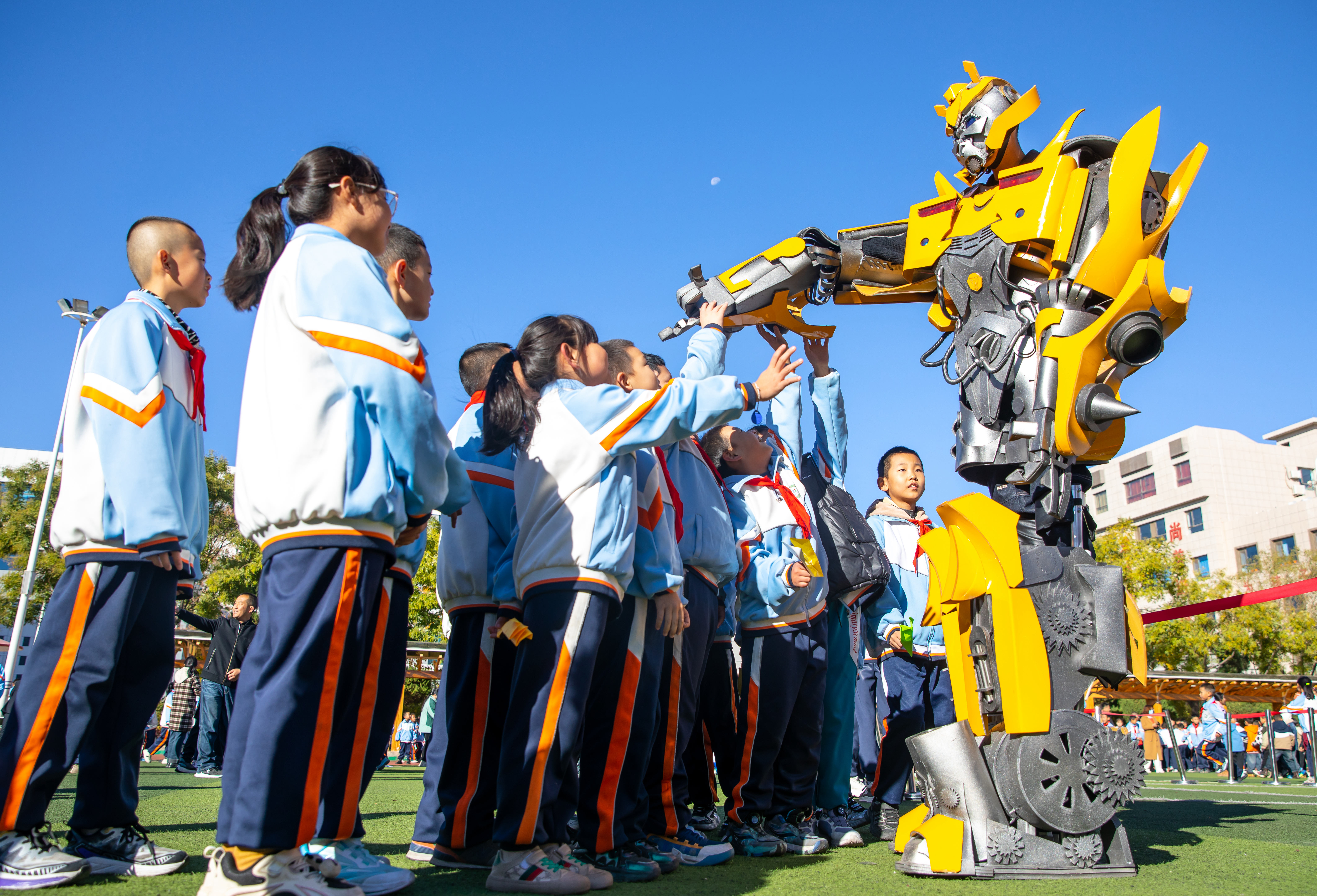 2024年10月22日，在甘肅省張掖市甘州區(qū)北街街小學(xué)科技大篷車嘉年華活動(dòng)上，學(xué)生與“大黃蜂”機(jī)器人互動(dòng)。楊瀟 攝.jpg