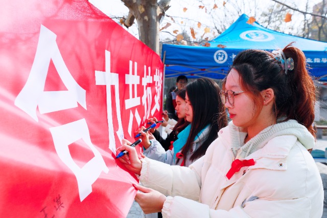 20231127中國石油大學(xué)（華東）青年學(xué)子在合力共抗艾滋的條幅上簽字，表達(dá)抗擊艾滋病的決心和信心  .jpg
