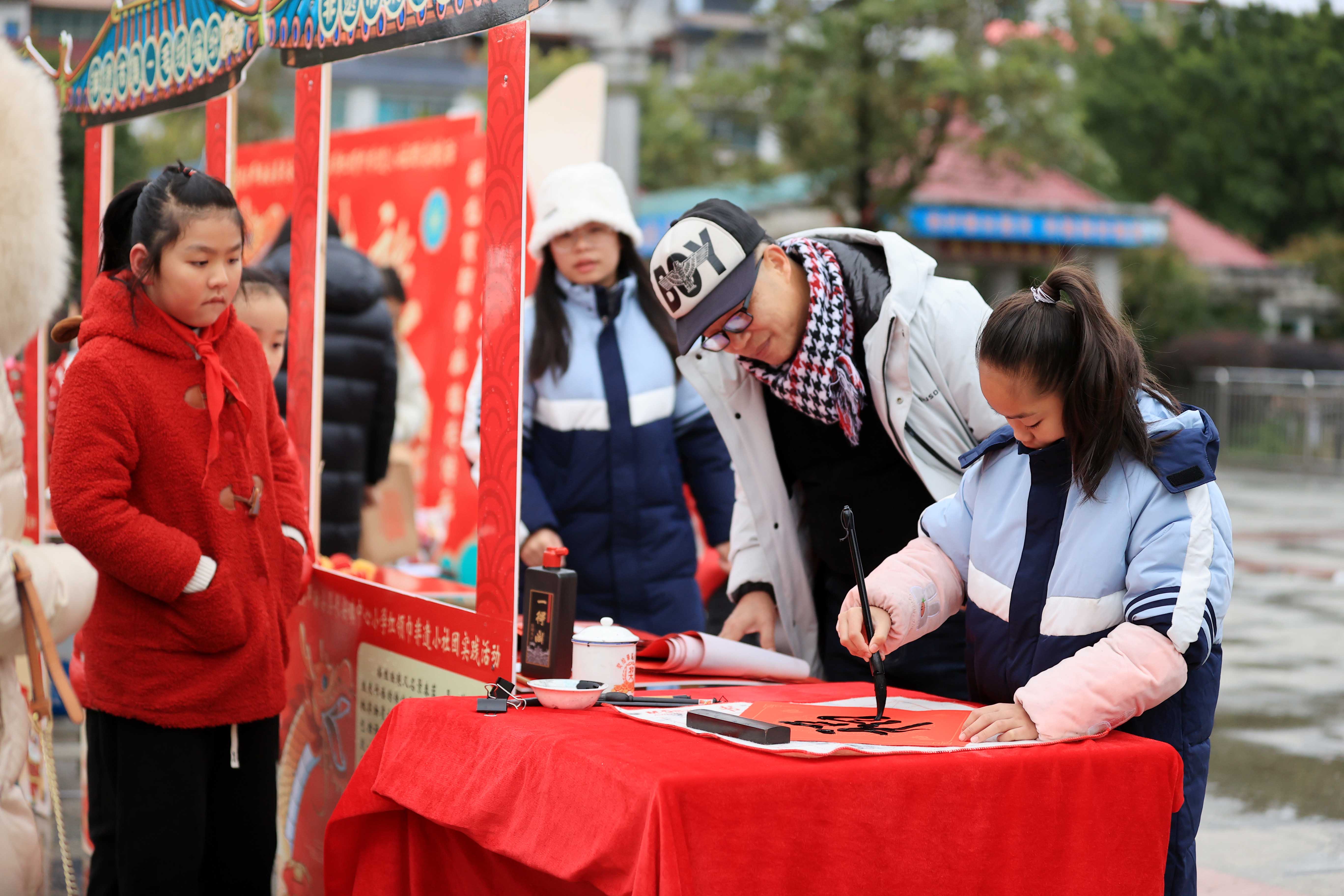 圖10：1月20日，在廣西柳州市融安縣長安廣場，一名小學生在書寫福字，準備贈送市民。（譚凱興 攝）.JPG