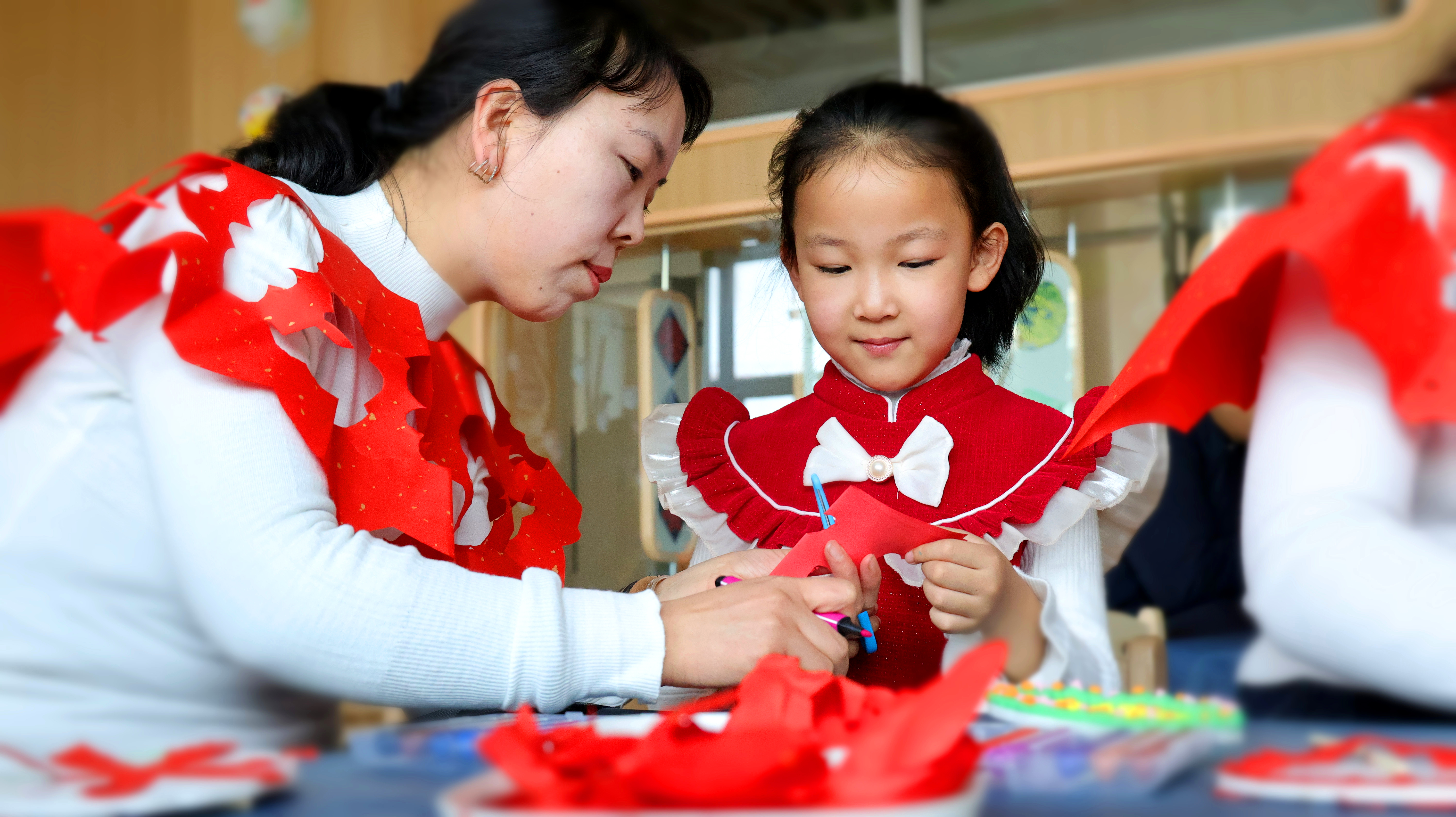 幼兒和媽媽一起用剪紙的方式制作云肩。宋雪蓮攝.jpg